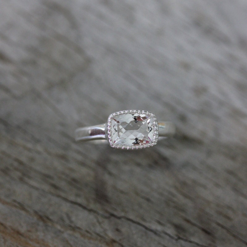 A handmade engagement ring with a Vintage Inspired White Topaz Cushion Cut Ring in Sterling Silver and Miligrain Bezel by Cassin Jewelry.