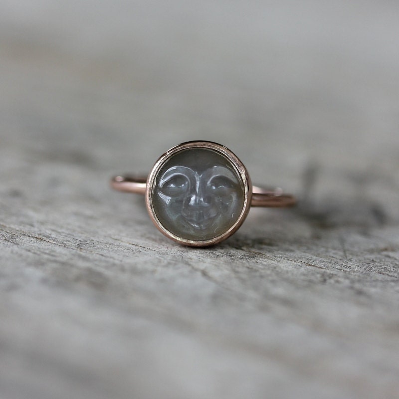 A Handmade Cassin Jewelry Man in the Moon Rose Gold Black Moonstone Ring with a moon face on it.