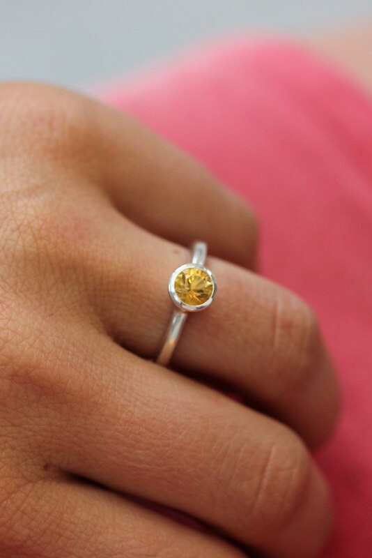 A woman wearing a handmade jewelry with a Round Citrine Ring featuring a yellow stone.