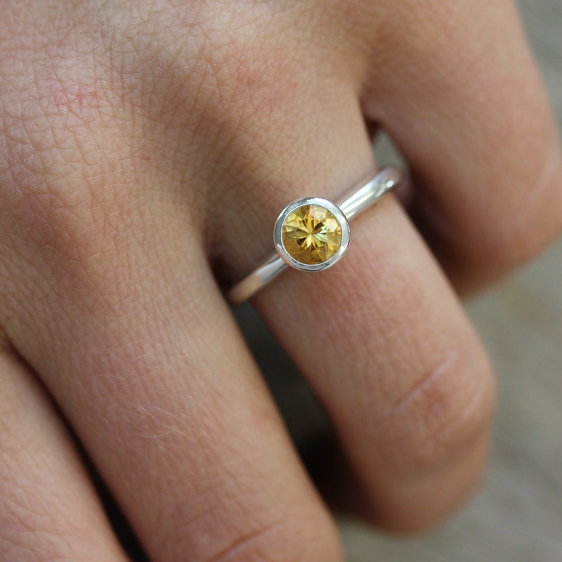 A woman's hand is holding a handmade Round Citrine Ring.