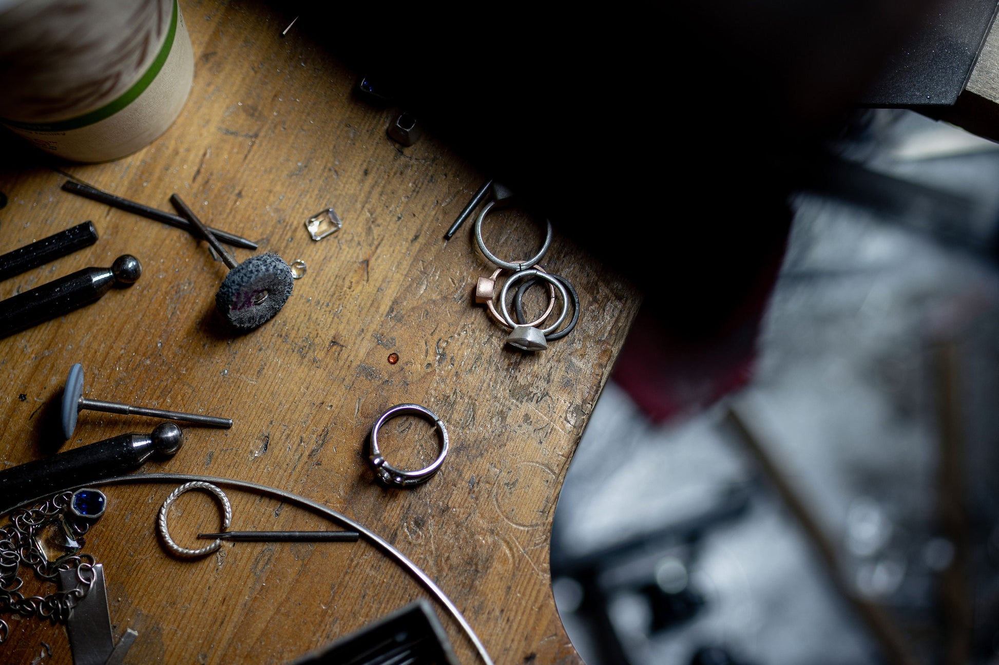 A bunch of handmade Man in the Moon Rose Gold Black Moonstone Rings and tools on a table.