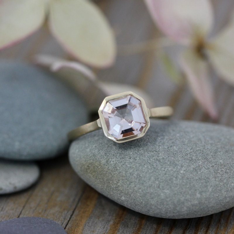 A handmade Asscher Cut Morganite Ring in 14k yellow Gold with a pink sapphire stone.