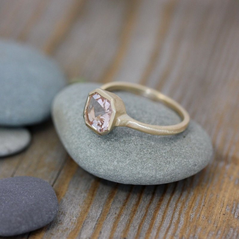Handmade Cassin Jewelry featuring an Asscher Cut Morganite Ring in 14k yellow Gold with a morganite stone on top of rocks.