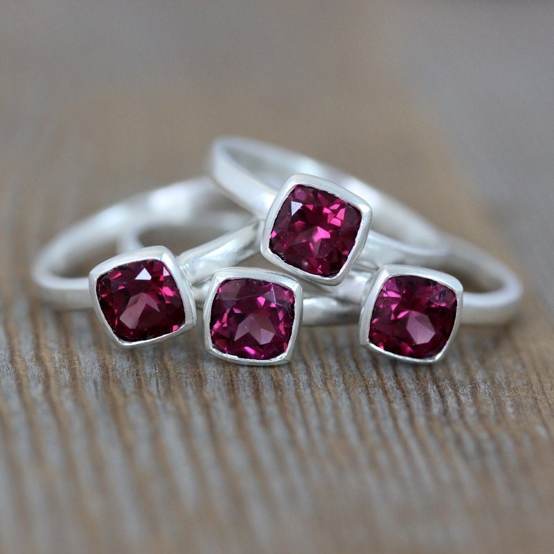 Three handmade Pink Garnet Rings on top of a wooden table.