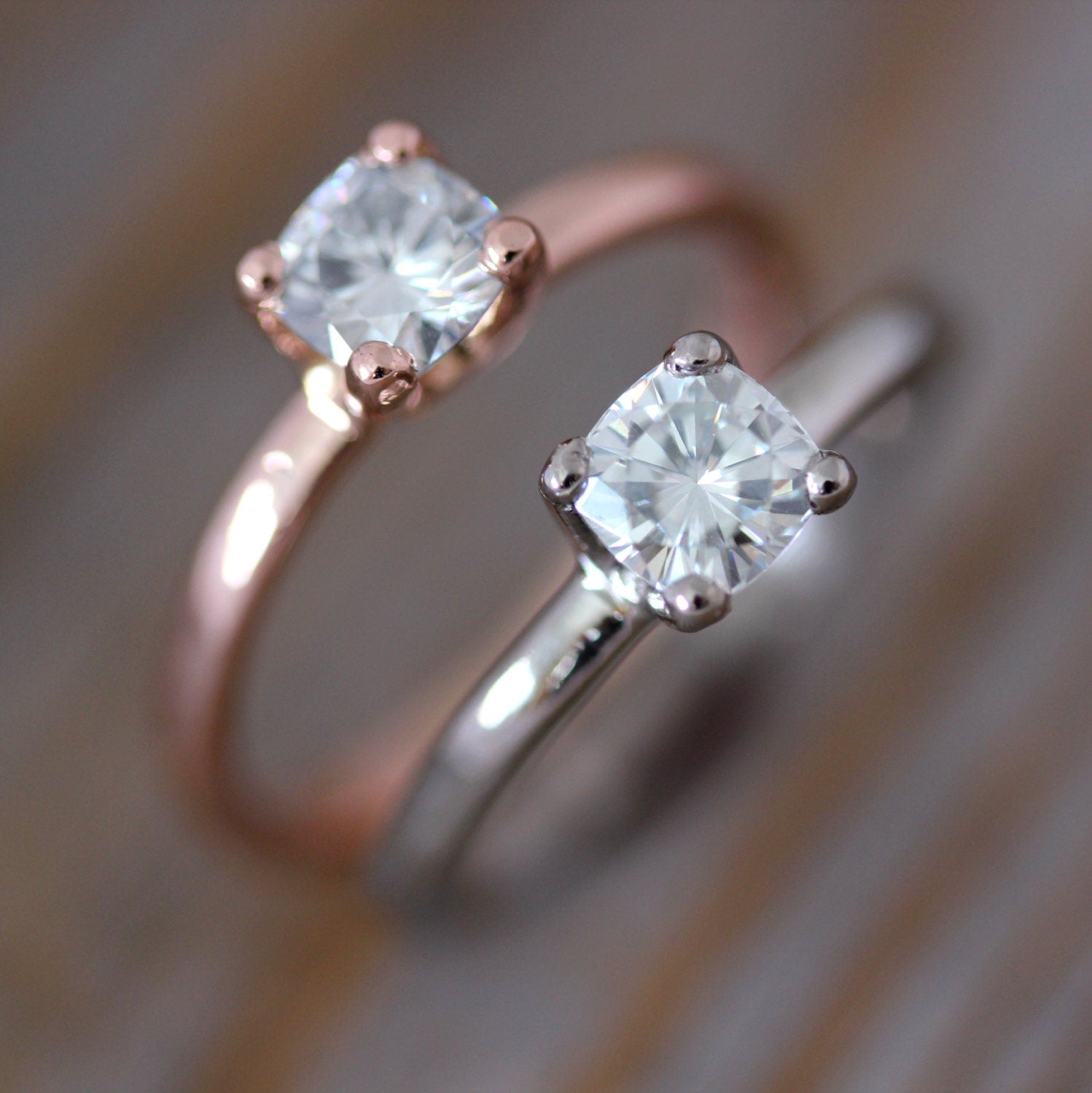 Two handmade Rose Gold and Moissanite engagement rings on top of each other.