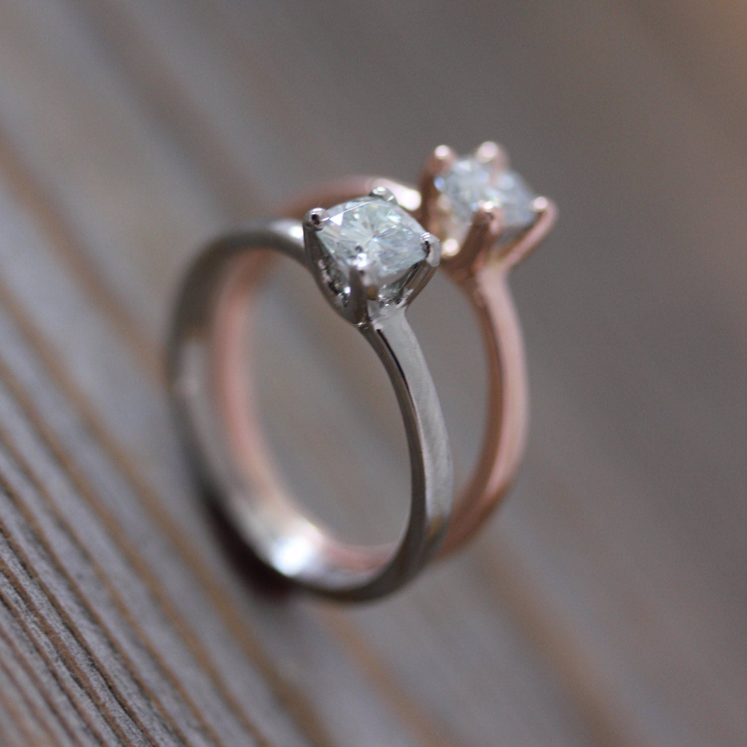 Two Handmade Rose Gold Engagement Rings on a Wooden Table