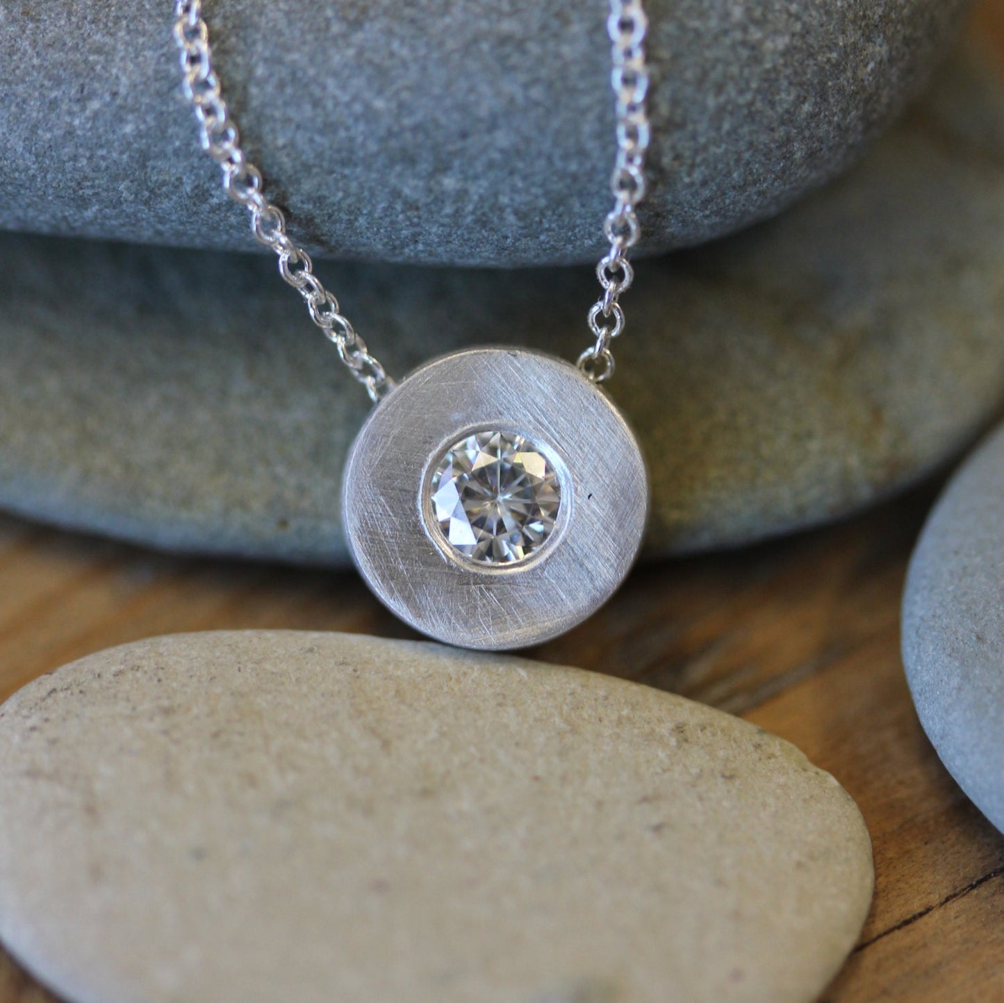 A handmade Moissanite and Sterling Silver Slide Pendant with a diamond on it by Cassin Jewelry.