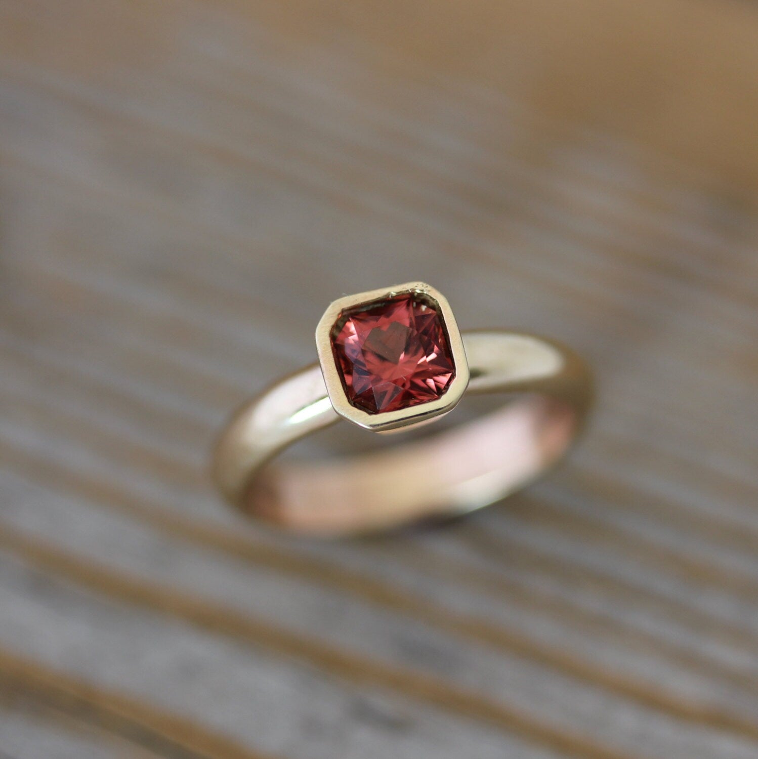 A handmade Asscher Cut Pink Spinel Ring in 14k Yellow Gold with a red garnet stone, crafted by Cassin Jewelry.