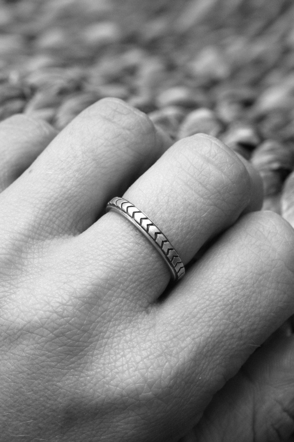 A black and white photo of a person wearing a handmade Chevron Wedding Band in Silver by Cassin Jewelry.