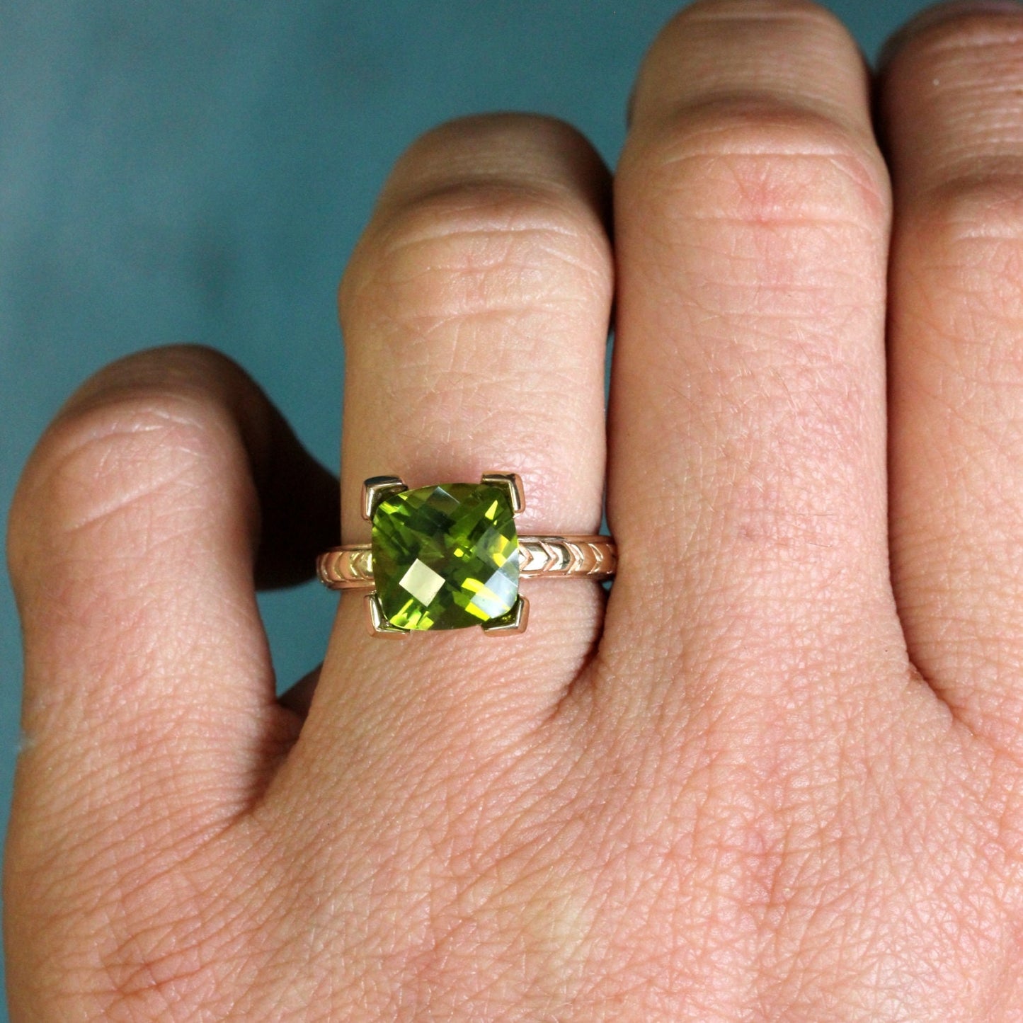 A woman's hand holding a Cushion Cut Peridot Yellow Gold Ring by Cassin Jewelry.