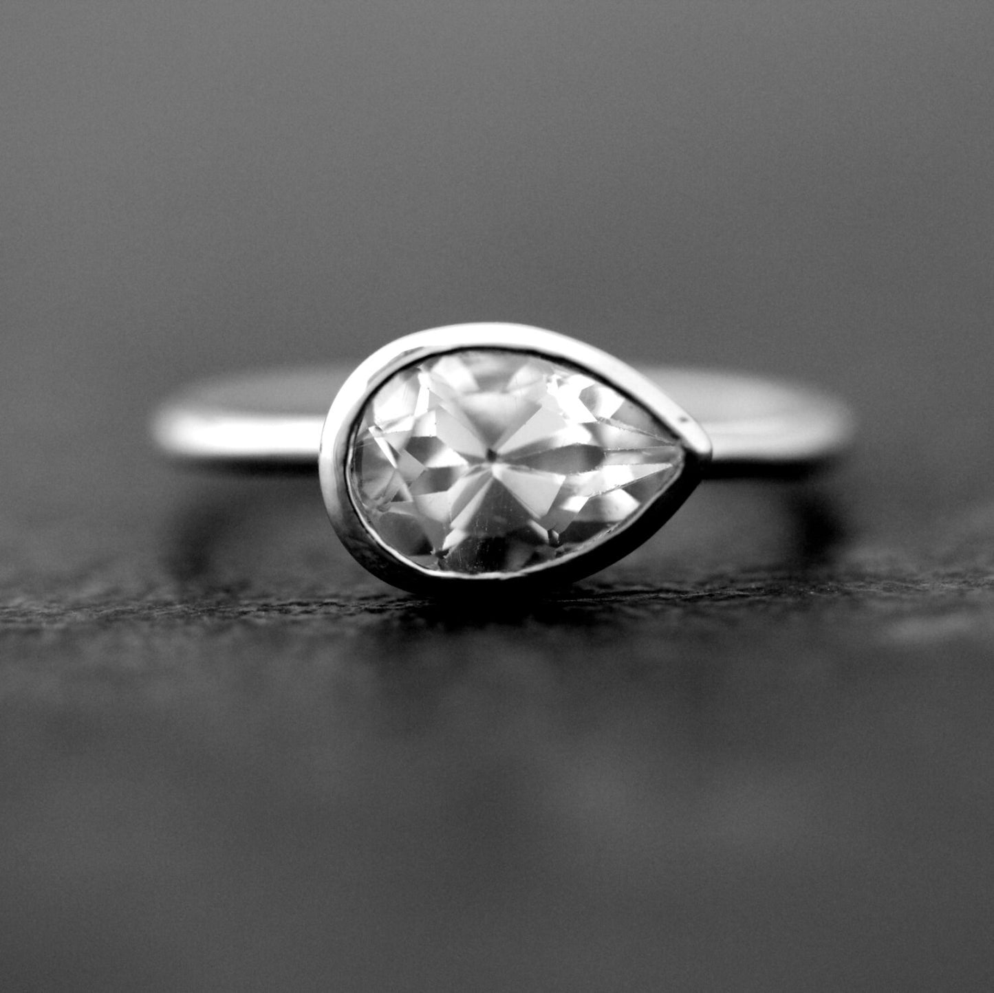 Handmade jewelry featuring a Sideways White Topaz Pear Shape Gemstone Ring in Sterling Silver Bezel by Cassin Jewelry.