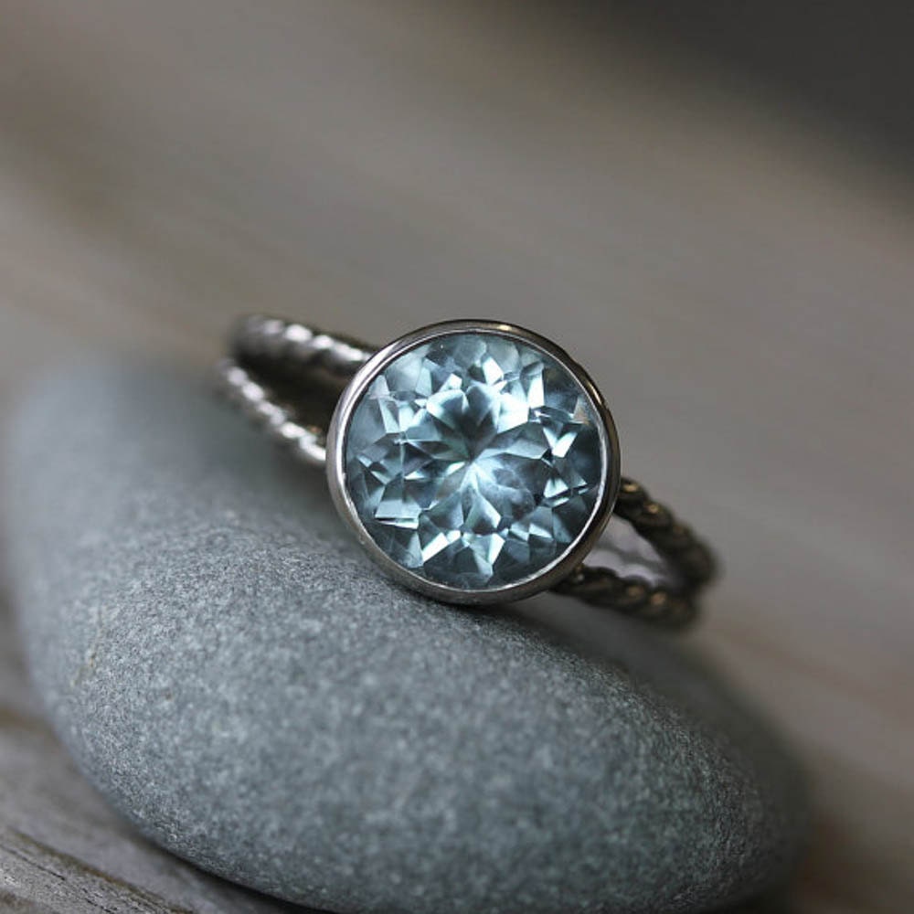 Handmade jewelry featuring a round aquamarine split shank setting in sterling silver with a blue topaz stone on top.