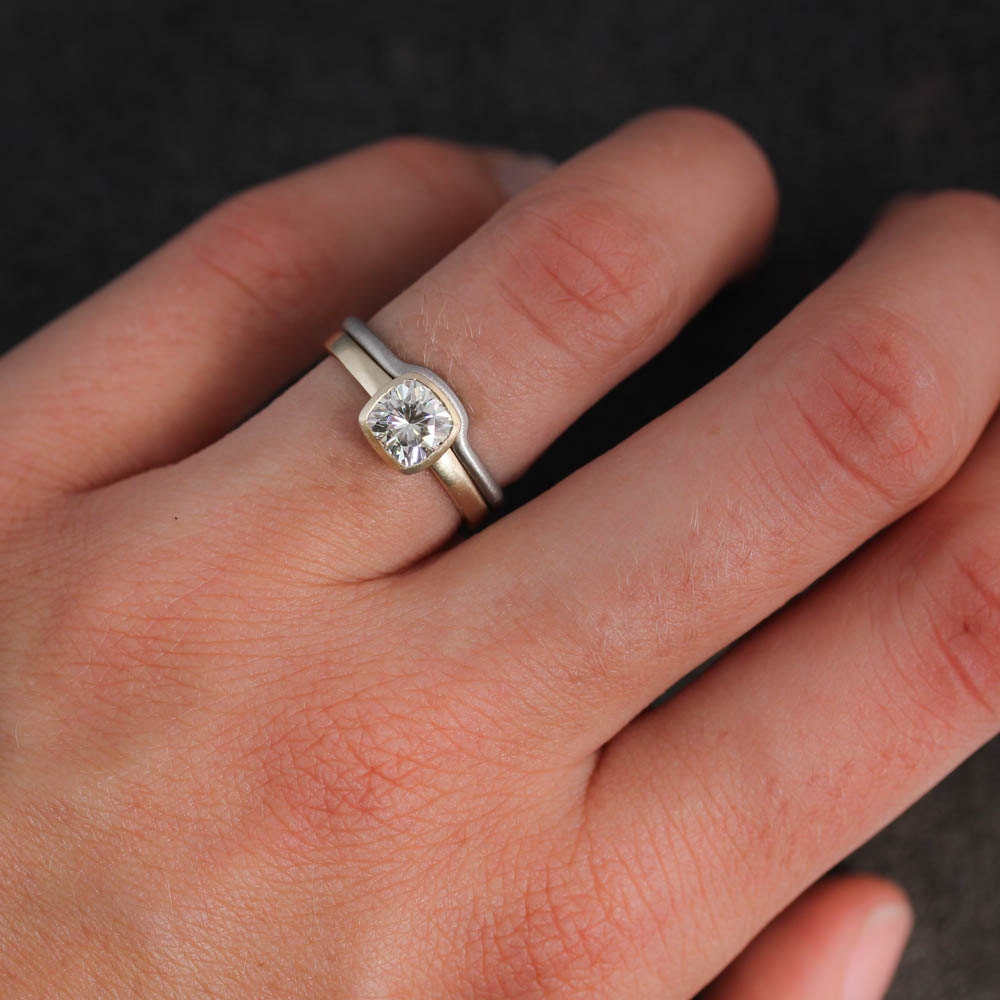 A woman's hand with a Moissanite Engagement Ring and Wedding Band Set from Cassin Jewelry.