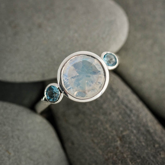 Handmade jewelry featuring a Rainbow Moonstone Three Stone Ring and a Blue Topaz Ring by Cassin Jewelry.