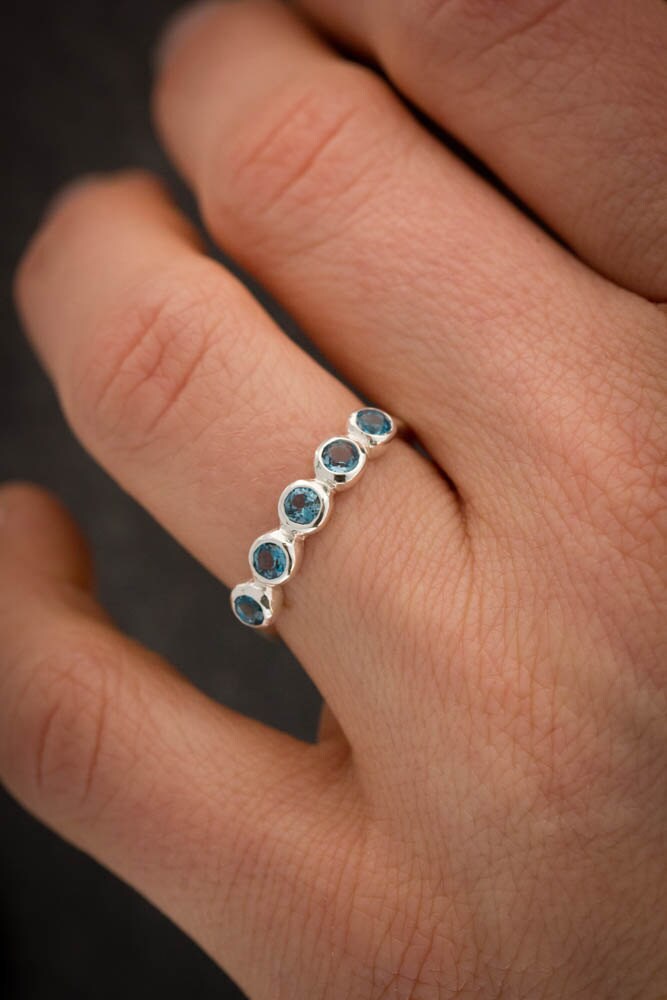 A woman's hand holding a London Blue Topaz Multistone Ring crafted by Cassin Jewelry.