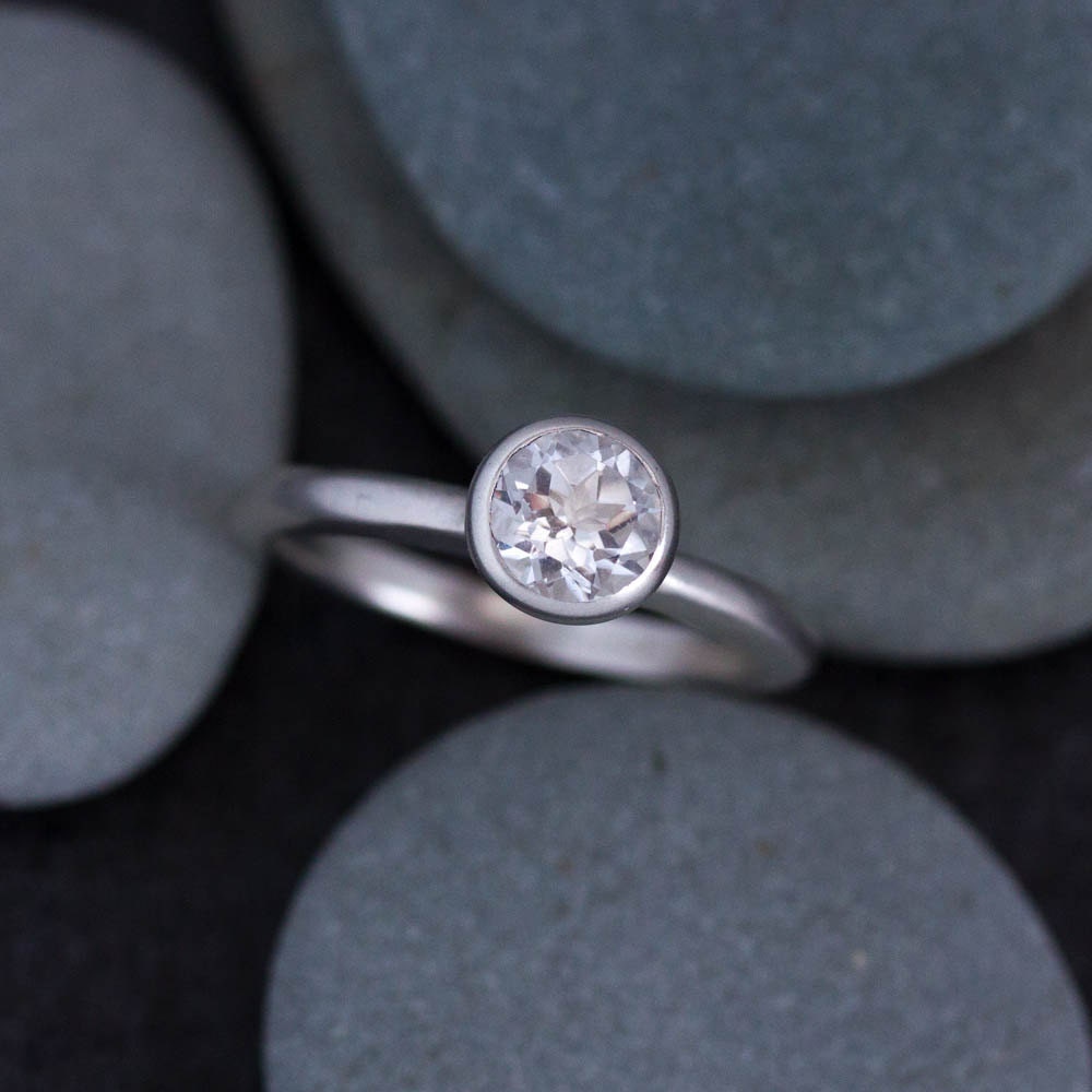 A handmade engagement ring with a white diamond on top of rocks.