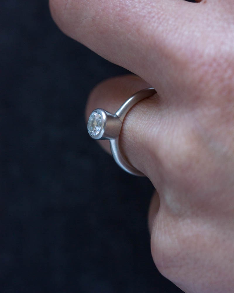 A person wearing a handmade Simple Engagement Ring with a diamond on it.