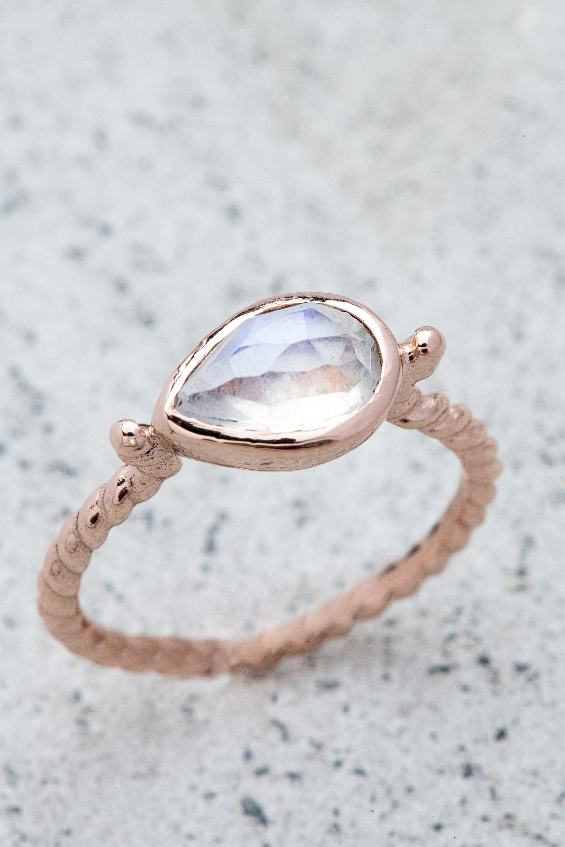 A handmade rose gold ring with a Pear Shaped Rainbow Moonstone.