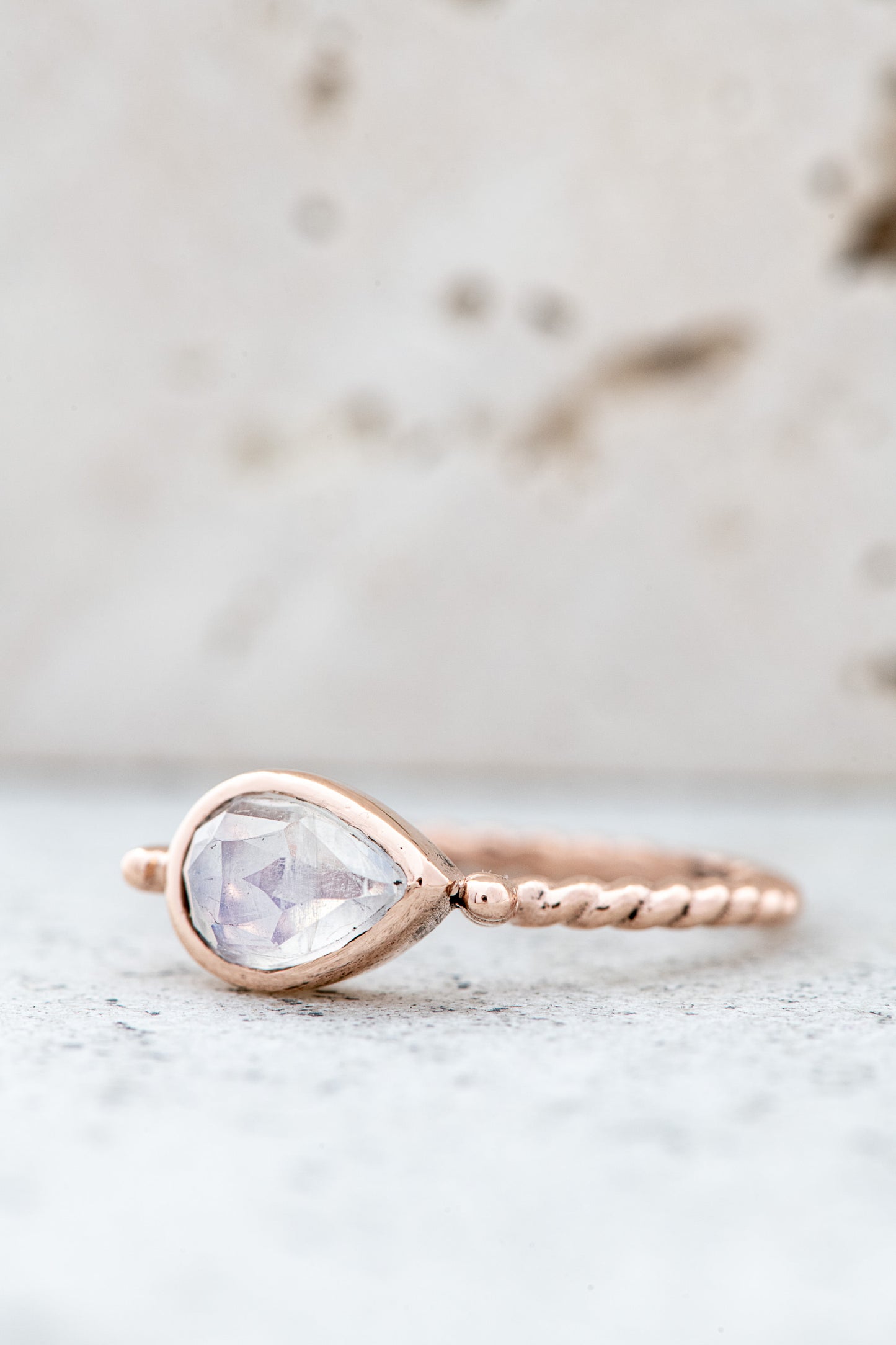 A handmade rose gold ring with a Pear Shaped Rainbow Moonstone.